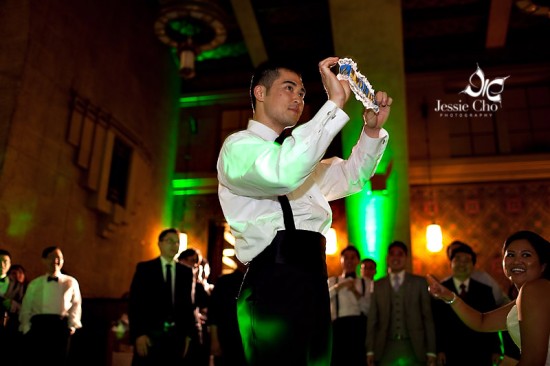 Groom playfully holds garter at wedding reception