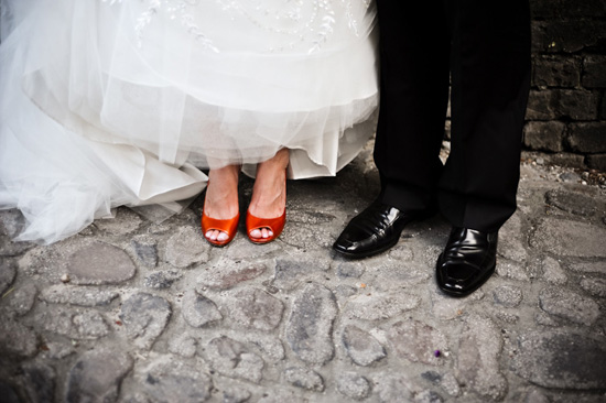 Bride in wedding dress with bright orange shoes and groom's black shoes