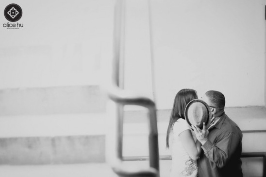 Couple sharing a kiss behind a hat in monochrome photograph