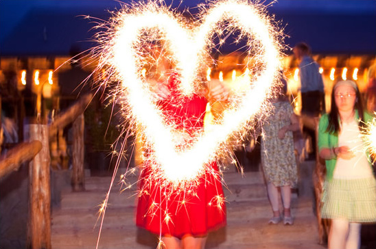 Person holding sparklers in the shape of a heart at night