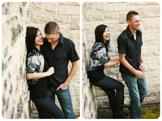 Happy couple laughing and playfully leaning against a stone wall