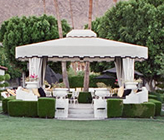 Elegant outdoor gazebo with seating surrounded by manicured hedges