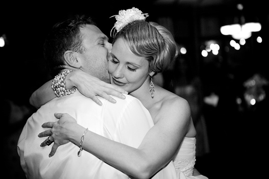 Loving embrace: Groom kisses bride on the dance floor in black and white