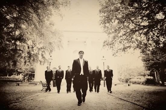 Groom and groomsmen walk towards camera at a wedding