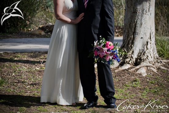 Bride and groom embracing with a bouquet next to a tree on their wedding day