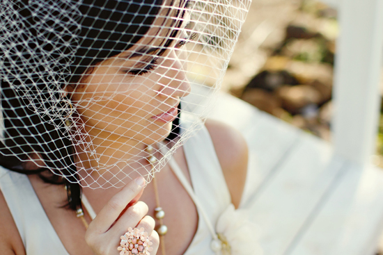 Bride wearing a birdcage veil and pearl jewelry