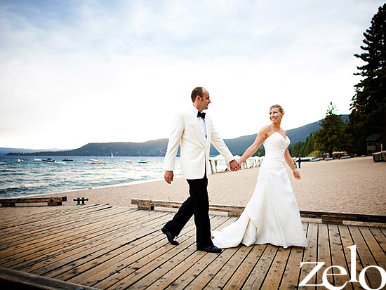 Bride and groom walk on dock by lake at wedding