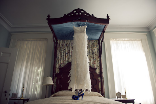 Feathered wedding dress and blue heels on four poster bed