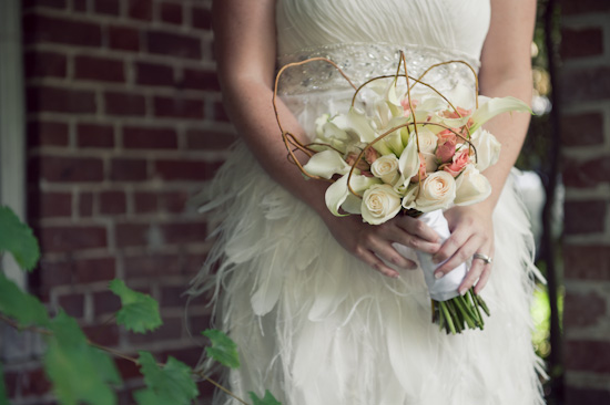 Bride holds floral bouquet in a feather wedding gown