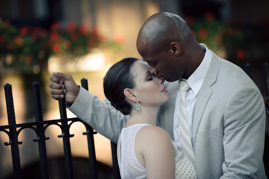 Newlyweds share a tender kiss by an iron fence