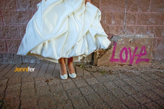 Bride's shoes dress and love graffiti on brick wall