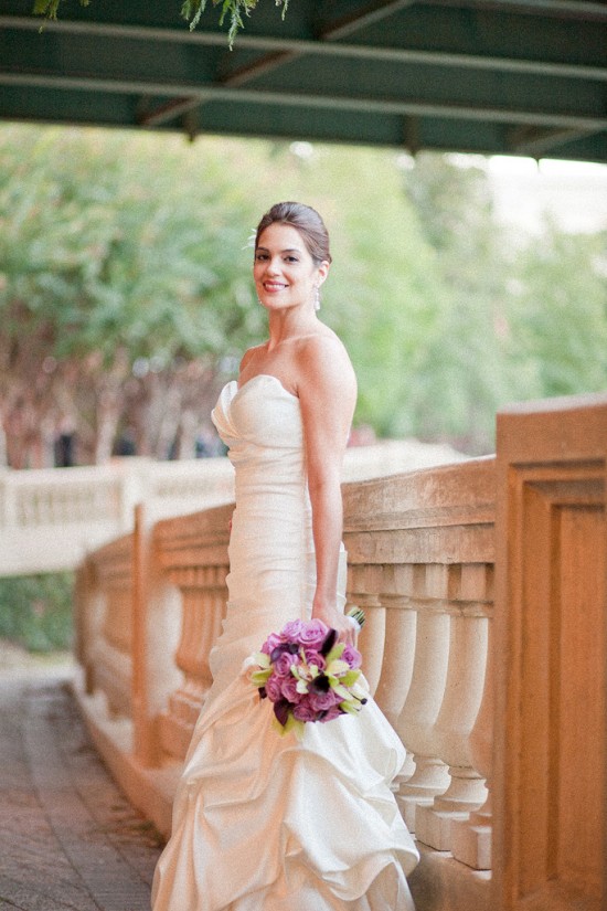 Beautiful bride in gown holding purple bouquet