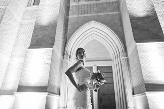 Black and white photo of bride with church door