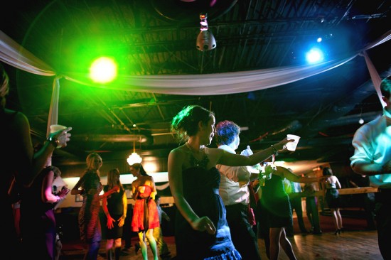 Partygoers dance under colorful lights at a lively event