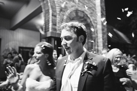 Happy couple exits wedding reception, showered with confetti