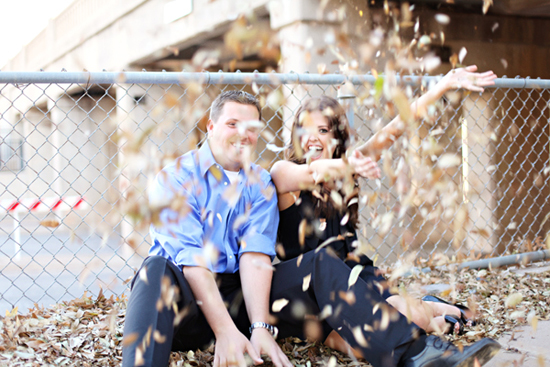 Happy couple laughing as leaves are thrown in the air