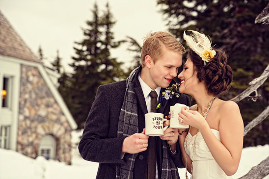 Romantic couple holding coffee mugs in winter wedding setting