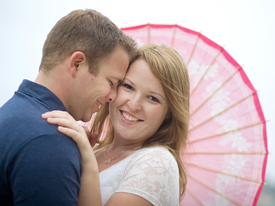 Happy couple embracing under pink parasol