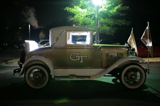 Vintage car with GT logo on the side at night with flags