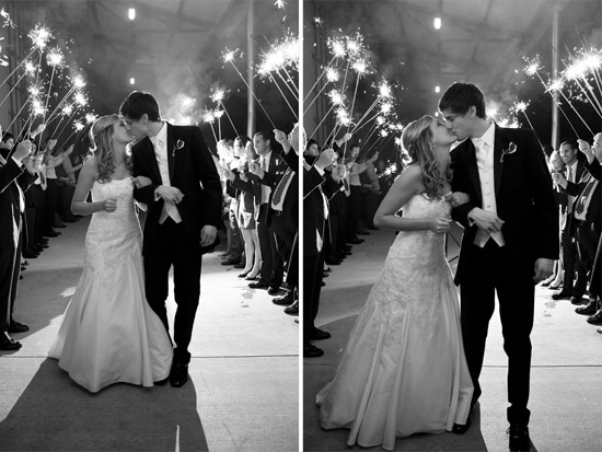 Newlyweds share a kiss under a sparkler wedding exit in black and white