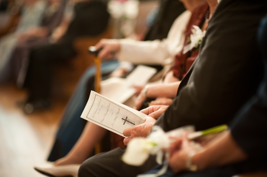 People in pews at a church service holding a program