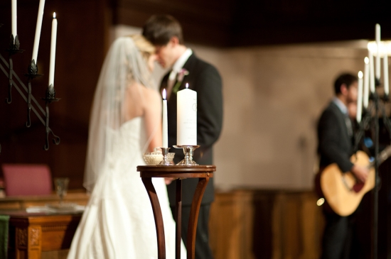 Bride and groom at wedding ceremony with candles and guitarist