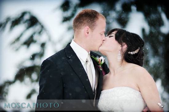 Bride and groom share a kiss in a snowy winter wedding photo