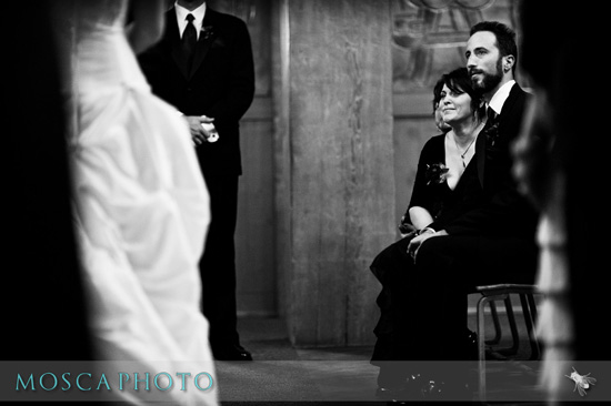 Wedding ceremony guests watching bride in black and white