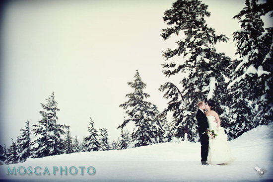 Winter wedding couple kissing in snow with snowy trees