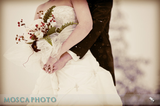 Bride and groom embrace on wedding day with a winter bouquet