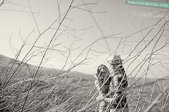 Black and white photo of a couple embracing in field