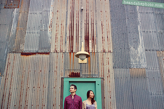 Couple stands before rusty metal wall