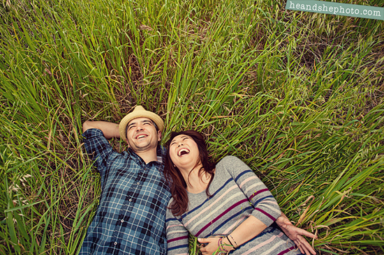 Happy couple laying in tall grass, laughing