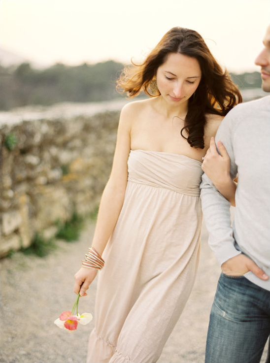 Woman in strapless dress holding flowers walks with a man