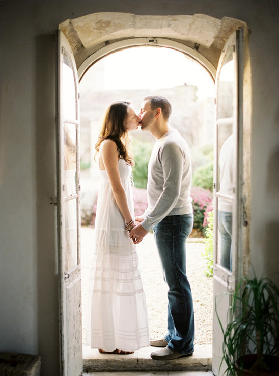 Couple sharing a kiss in a doorway, holding hands and embracing