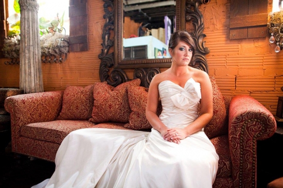Bride in white gown sits on ornate couch