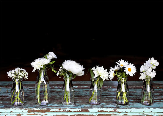 White flowers in vintage bottles on a rustic table