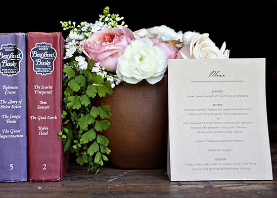 Vintage books floral arrangement and menu card on wood