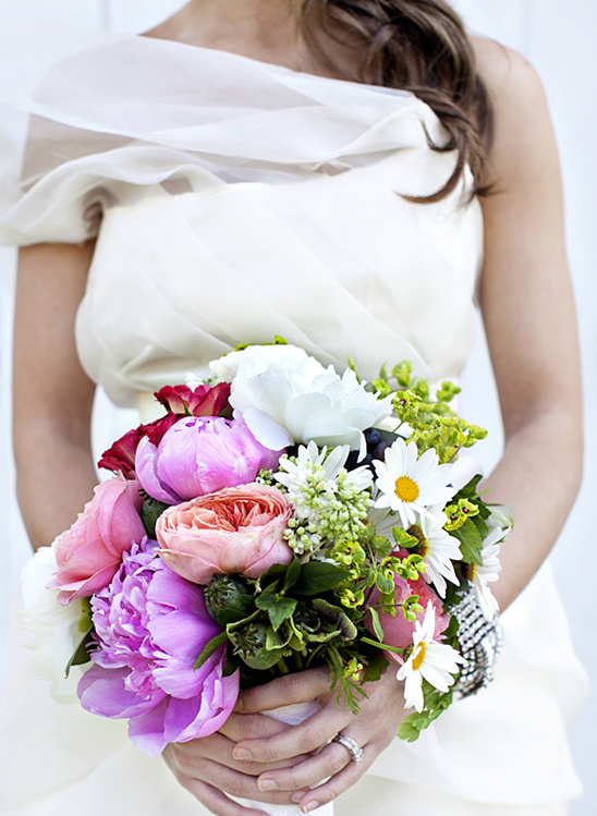 Bride in gown holding colorful peony bouquet