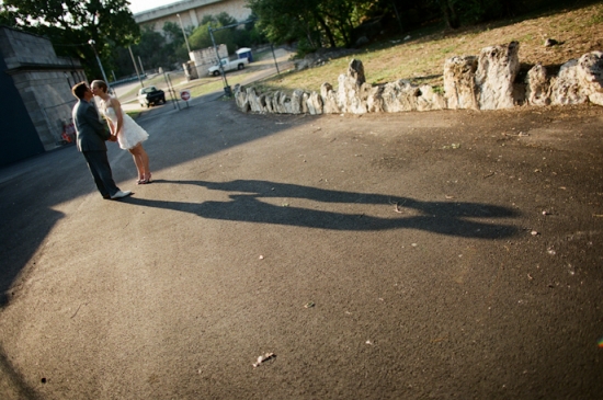 Bride and groom kiss casting long shadows outdoors