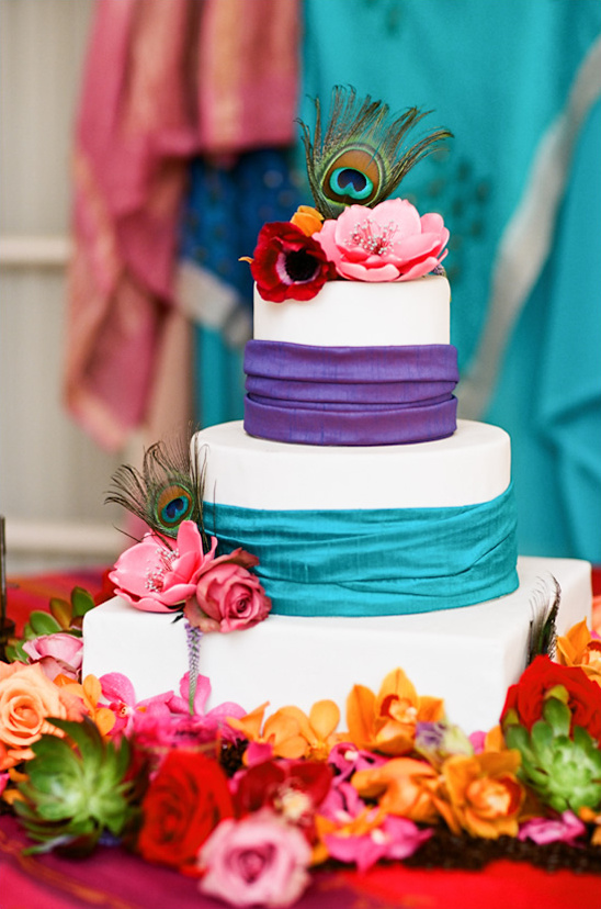 Colorful wedding cake with peacock feather and vibrant flowers