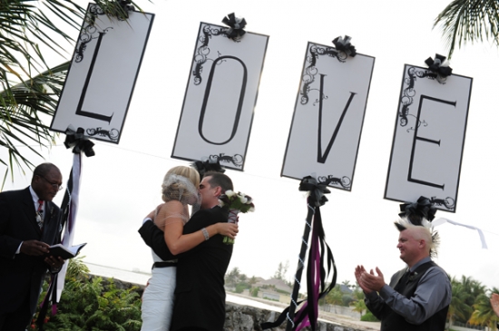 Bride and groom kissing with LOVE sign at wedding