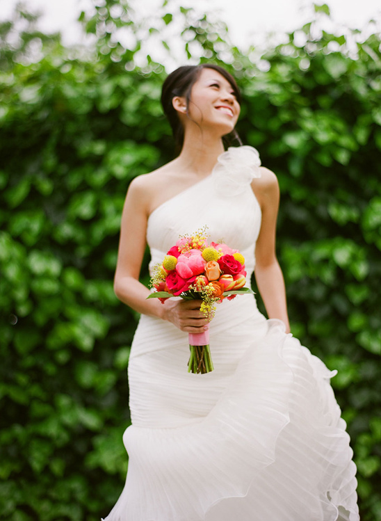 Bride in white dress holding vibrant bouquet