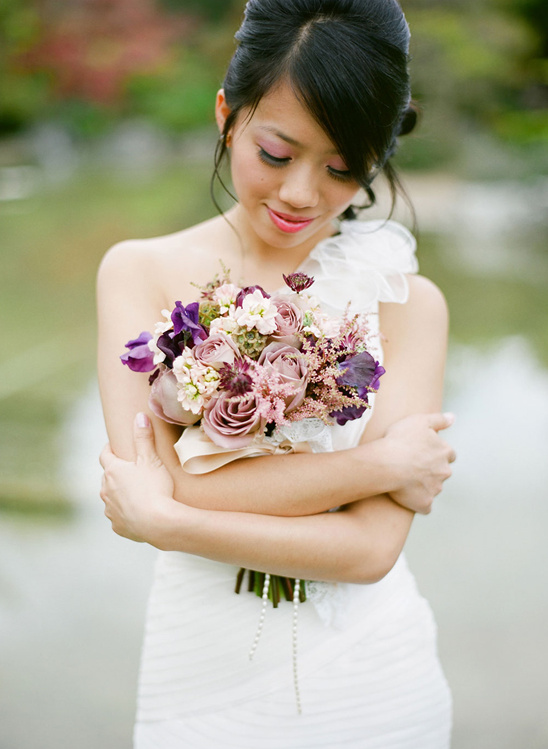 Bride in white dress holding purple wedding bouquet