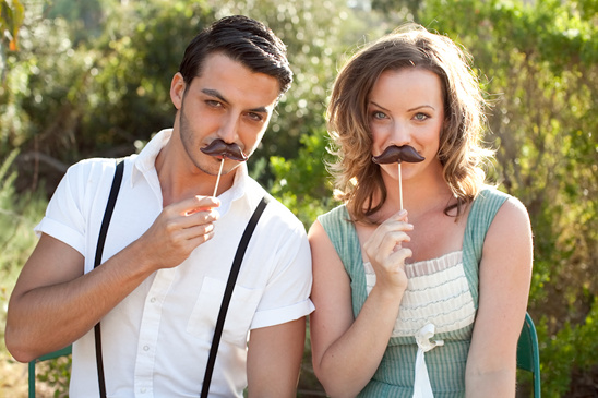 Couple poses with funny mustache props outdoor