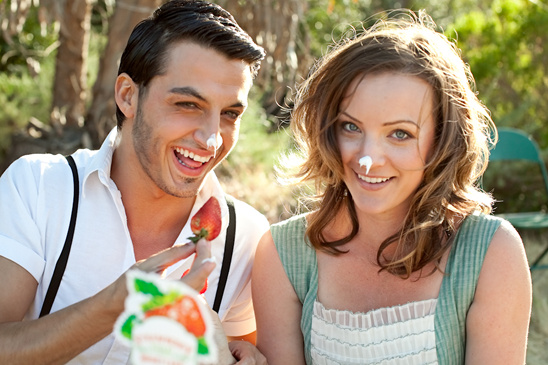 Happy couple enjoying strawberries with cream outdoors