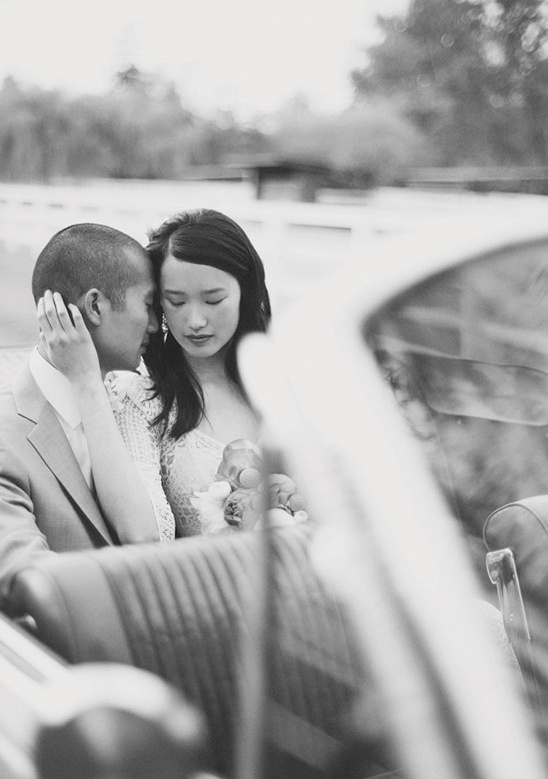 Black and white photo of a loving wedding couple in car