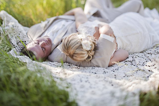 Bride and groom napping on a lace blanket in grass