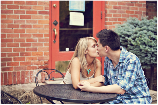 Couple kissing outdoors in front of brick building