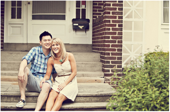 Smiling couple sits on front porch steps of brick home